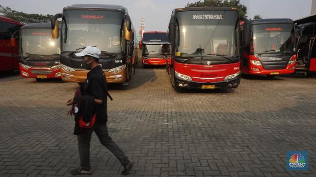 Petugas merapihkan deretan bus di Pool Bus Pariwisata Kawasan Tanjung Barat, Jakarta Selatan, Selasa (28/7/2020). Masih diberlakukannya Pembatasan Sosial Bersekala Besar (PSBB) dan penutupan tempat rekreasi akibat Covid-19, berimbas pada jasa transportasi pariwisata. 

Penutupan obyek wisata dan imbauan untuk tidak ke tempat keramaian demi mencegah penyebaran corona (covid-19) membuat Perusahaan Otobus (PO) pariwisata mengandangkan armadanya. Padahal, momen sebelum datangnya Ramadhan merupakan waktunya para pemilik perusahaan otobus panen rezeki.
PO terpaksa mengandangkan armadanya karena berbagai acara keluar kota dibatalkan. Permasalahan tak berhenti di situ saja, bayang-bayang setoran cicilan ke perusahaan leasing juga menghantui para pemilik PO ini. 

Fajar, Head Marketing bus Manhattan, pada CNBC Indonesia, menjelaskan para usaha bus sejak pandemi ini terpuruk. Apalagi, menurut Fajar, pesanan bus biasanya sudah ramai lagi pada H-7 Lebaran kemarin.

Dengan kondisi seperti ini, banyak bus yang dikandangkan, akibatnya membuat pemasukan tidak ada.

