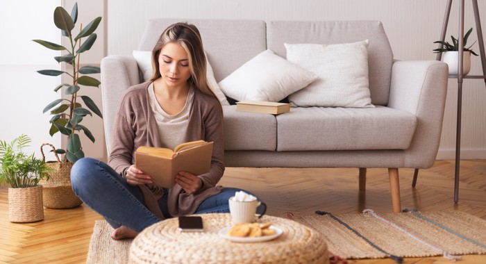 Ilustrasi hobi membaca buku Self education concept. Young woman reading book, sitting on floor at home, panorama, free space