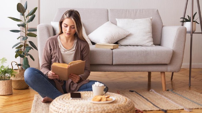 Ilustrasi hobi membaca buku Self education concept. Young woman reading book, sitting on floor at home, panorama, free space