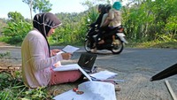 Potret mahasiswa jurusan manajemen Universitas Muhammadiyah Magelang Teara Noviani yang terpaksa mengerjakan Ujian Tengah Semester secara daring di pinggir jalan kawasan pegunungan Menoreh di Desa Kenalan, Borobudur, Magelang, Jawa Tengah karena kesulitan mendapatkan sinyal internet di wilayahnya. ANTARA FOTO/Anis Efizudin.