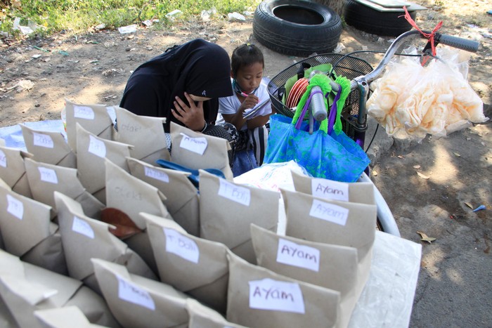 Pelajar kelas VIII MTs Darul Ulum, Sovi Dwi Aprilia (kiri) bersama adiknya, Tri Wahyu, yang masih kelas I SD belajar sambil berjualan nasi bungkus di pinggir jalan kawasan Delta Sari, Waru, Sidoarjo, Jawa Timur, Selasa (28/7/2020). Sovi berjualan nasi untuk membantu orangtuanya sekaligus mencari tambahan untuk membeli paket data internet agar bisa belajar secara daring. ANTARA FOTO/Umarul Faruq/foc.