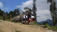 Para siswa mengerjakan tugas dengan beralaskan papan serta daun pohon aren sebagai atap untuk berteduh.