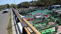 Sebuah mobil melintasi jembatan disamping Pangkalan Pendaratan Ikan (PPI) Binuangeun yang menjadi lokasi para nelayan menyandarkan kapal-kapalnya usai tak melaut sejak beberapa waktu lalu.