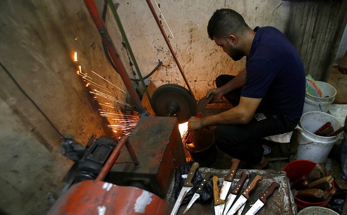 A Palestinian man sharpens a knife that will be used to slaughter cattle or cut meats during the Muslim festival of sacrifice Eid al-Adha, in a workshop in Gaza City, Tuesday, July 28, 2020. Eid al-Adha, or Feast of Sacrifice, Islam's most important holiday marks the willingness of the Prophet Ibrahim to sacrifice his son. (AP Photo/Hatem Moussa)