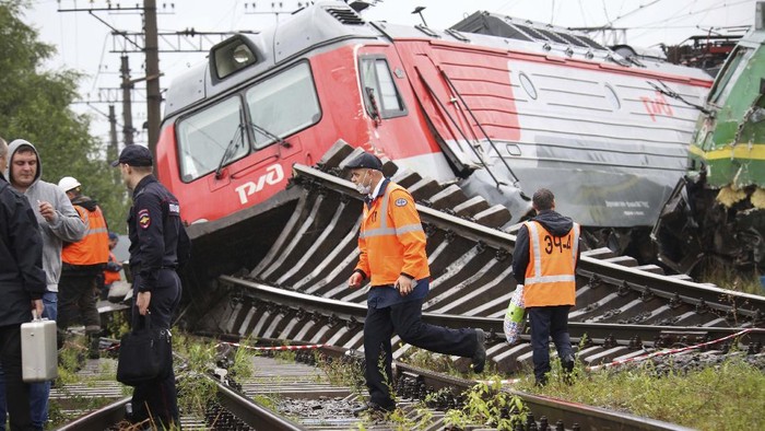 Railway workers stand at the site of the collision of two freight trains at the Kupchinskaya railway station in outskirts of in St. Petersburg, Russia, Tuesday, July 28, 2020. According to the Russian Ministry of Emergency Situations, there is no delay in passenger trains, a bypass route has been organized. As a result of the emergency, two people were injured, one of them refused hospitalization. (AP Photo)
