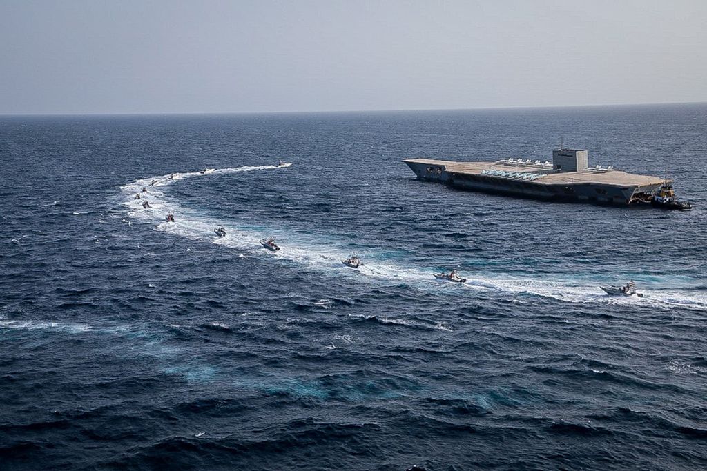 In this photo released Tuesday, July 28, 2020, by Sepahnews, Revolutionary Guard's speed boats circle around a replica aircraft carrier during a military exercise. Iran's paramilitary Revolutionary Guard has fired a missile from a helicopter targeting the mock-up aircraft carrier in the strategic Strait of Hormuz according to footage aired on state television on Tuesday. Iranian commandos also fast-roped down from a helicopter onto the replica in the footage from the exercise called 