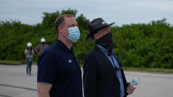 Administrator NASA Jim Bridenstine (kiri) bersama Presiden dan CEO United Launch Alliance Tony Bruno sambil memakai masker menyaksikan pemindahan roket Atlas V dari Vertical Integration Facility menuju landasan peluncuran. Foto: NASA/Joel Kowsky