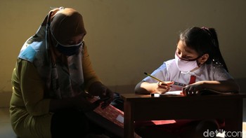 Seorang siswa mengerjakan soal via online dengan dibantu orangtuanya.