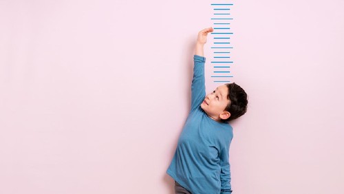 Child measuring his height on wall. He is growing up so fast.