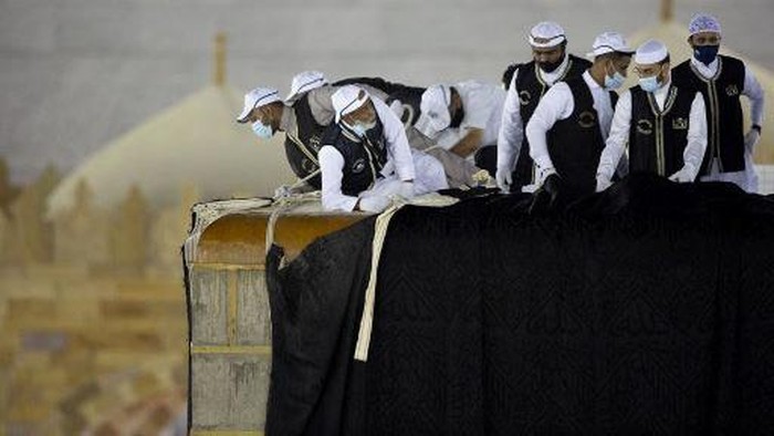 Melihat Penggantian Kain Kiswah Saudi labourers put the new Kiswa, the protective cover that engulfs the Kaaba, made from black silk and gold thread and embroidered with Koran verses, on July 29, 2020 in Saudi Arabia's holy city of Mecca. - The drape which engulfs the Kaaba is formally called Kiswa and is changed every year at the culmination of the annual hajj, or pilgrimage, when the hajjis have left Mecca to go to Arafat, the starting point of their hajj journey. (Photo by - / AFP)