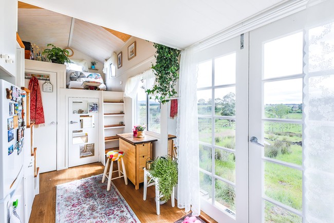 Terlepas dari ukurannya yang kecil, rumah tersebut tetap terasa luas berkat warna putih dan pintu kayu berkaca. Sejumlah tanaman hias mempermanis interior bagian dalam sehingga menciptakan kesan selaras dengan keindahan alam di luar. (Foto: Dok. Living Big in a Tiny House)