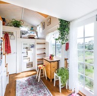 Terlepas dari ukurannya yang kecil, rumah tersebut tetap terasa luas berkat warna putih dan pintu kayu berkaca. Sejumlah tanaman hias mempermanis interior bagian dalam sehingga menciptakan kesan selaras dengan keindahan alam di luar. (Foto: Dok. Living Big in a Tiny House)