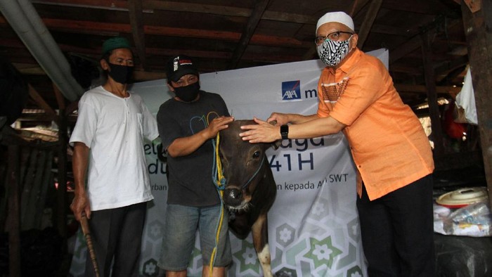 Direktur Kepatuhan PT AXA Mandiri Financial Services (AXA Mandiri) Rudy Kamdani (kanan) menyerahkan hewan kurban kepada perwakilan warga Kampung Pemulung Pelangi, Ustad Gandhi (kiri), di wilayah Cipete Utara, Antasari, Jakarta Selatan, Jumat (31/7).