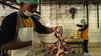 Petugas memotong daging menjadi kecil-kecil.