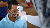 Petugas jagal hewan kurban cek suhu tubuh sebelum menjalani rapid test.