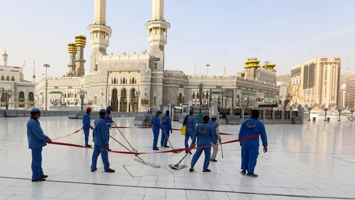 Workers clean and disinfect around the Kaaba on August 1, 2020, traced with lines for easing the physical distancing between pilgrims due to the coronavirus, during the evening before the last day of circumambulation around the shrine, in the Grand mosque of the holy Saudi city of Mecca, during the annual Muslim Hajj pilgrimage (Photo by - / AFP)