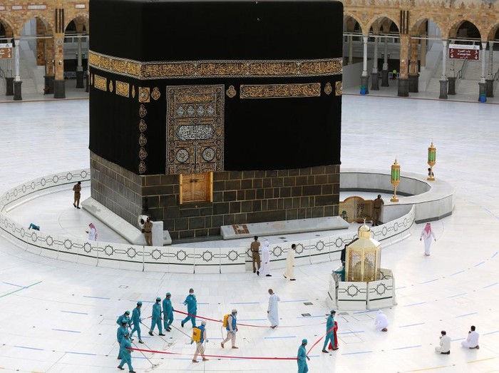 Workers clean and disinfect around the Kaaba on August 1, 2020, traced with lines for easing the physical distancing between pilgrims due to the coronavirus, during the evening before the last day of circumambulation around the shrine, in the Grand mosque of the holy Saudi city of Mecca, during the annual Muslim Hajj pilgrimage (Photo by - / AFP)