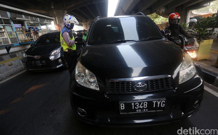Petugas polisi sosialisasi secara langsung kepada pengemudi yang melanggar Ganjil Genap di Perempatan Rawamangun, Jalan Pramuka, Jakarta Timur, Senin (3/8/2020). Sistem ganjil kendaraan bermotor di 25 ruas jalan di DKI Jakarta kembali berlaku mulai hari ini, Senin (3/8).