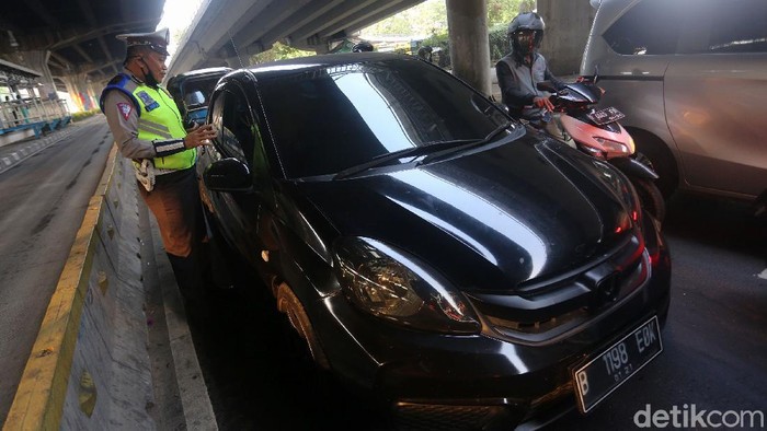 Petugas polisi sosialisasi secara langsung kepada pengemudi yang melanggar Ganjil Genap di Perempatan Rawamangun, Jalan Pramuka, Jakarta Timur, Senin (3/8/2020). Sistem ganjil kendaraan bermotor di 25 ruas jalan di DKI Jakarta kembali berlaku mulai hari ini, Senin (3/8).