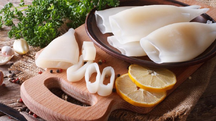 Sliced raw squid with ingredients on the kitchen board closeup. Horizontal