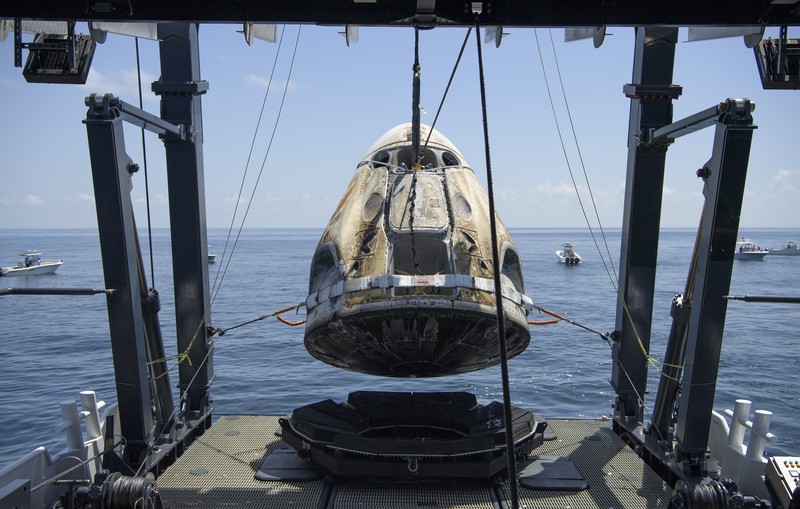 The SpaceX Crew Dragon Endeavour spacecraft is lifted onto the SpaceX GO Navigator recovery ship shortly after it landed with NASA astronauts Robert Behnken and Douglas Hurley onboard in the Gulf of Mexico off the coast of Pensacola, Fla., Sunday, Aug. 2, 2020. The Demo-2 test flight for NASA's Commercial Crew Program was the first to deliver astronauts to the International Space Station and return them safely to Earth onboard a commercially built and operated spacecraft. Behnken and Hurley returned after spending 64 days in space. (Bill Ingalls/NASA via AP)