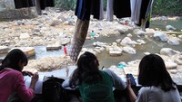 Mereka asyik belajar secara daring di pinggir sungai Ciliwung yang kering di perkampungan padat penduduk agar mendapatkan jaringan internet yang baik dalam mengerjakan tugas-tugas sekolah di masa pandemi COVID-19. 