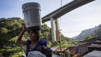 Seorang wanita membawa ember berisi air ke rumahnya di pemukiman Dios es Fiel di Guatemala.  