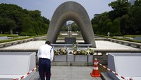 Seorang penjaga keamanan memberikan penghormatan di depan monumen peringatan untuk para korban bom Hiroshima yang berada di area sekitar Hiroshima Peace Memorial Museum, Jepang.