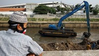 Ekskavator menyusuri Ciliwung untuk mengeruk lumpur yang mengendap di dasar sungai.