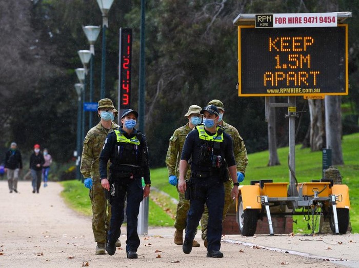 Police officers and soldiers patrol a popular running track in Melbourne on August 4, 2020 after the state announced new restrictions as the city battles fresh outbreaks of the COVID-19 coronavirus. - Australias Victoria state imposed fresh, sweeping restrictions on August 2, 2020, including a curfew in Melbourne for the next six weeks, a ban on weddings, and schools and universities going back online in the coming days. (Photo by William WEST / AFP)