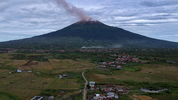Warga mengamati suasana perkampungan saat Gunung Kerinci mengembuskan gas dan material yang terlihat dari Gunung Tujuh, Kerinci, Jambi, Rabu (5/8/2020). Pos Pengamatan Gunung Api Kerinci menyebutkan Gunung Kerinci yang statusnya masih berada pada level II (waspada) kembali mengalami gempa embusan dan tremor menerus yang terpantau secara visual dan data seismik pada Rabu (5/8) pagi. ANTARA FOTO/Wahdi Septiawan/aww.