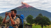 Warga mengamati suasana perkampungan saat Gunung Kerinci mengembuskan gas dan material yang terlihat dari Gunung Tujuh, Kerinci, Jambi, Rabu (5/8/2020).