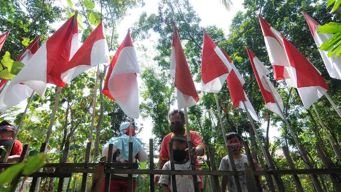 MEMASANG 75 BENDERA MERAH PUTIH Warga melintas di dekat bendera merah putih terpasang di kediaman Asim di Bayat, Klaten, Jawa Tengah, Rabu (5/8/2020). Asim melanjutkan tradisi turun temurun yang telah dilakukan sejak tahun 1995 oleh keluarganya dengan memasang bendera merah putih sebanyak usia negara Indonesia di rumahnya untuk memperingati HUT Kemerdekaan Republik Indonesia dan tahun ini ia memasang sebanyak 75 bendera merah putih sebagai edukasi kepada generasi muda agar tetap mencintai NKRI. ANTARA FOTO/Aloysius Jarot Nugroho/foc.
