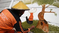 Petugas PPSU tampak teliti agar hasil mural sesuai dengan keinginan.
