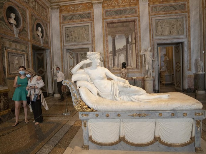 Women wearing masks to prevent the spread of COVID-19 walk past the sculpture Pauline Bonaparte as Venus Victrix graven by Antonio Canova between 1805 and 1808 at the Galleria Borghese art gallery, Wednesday, June 3, 2020. Italy opened regional and international borders Wednesday in the final phase of easing its long coronavirus lockdown. (AP Photo/Alessandra Tarantino)
