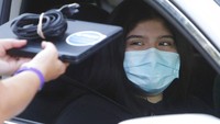 Wearing a mask to prevent the spread of COVID-19, Megan Steckly, CEO of Com-U-Dot, checks a driver in a line of cars as they wait to receive a computer during a drive through event in Dallas, Tuesday, Aug. 4, 2020. TXU Energy and Comp-U-Dopt partnered with the City of Dallas to give away 400 computers to middle school students to use when school starts. (AP Photo/LM Otero)