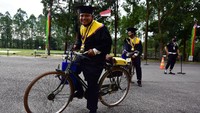 Sejumlah mahasiswa menggunakan sepeda ontel saat wisuda drive thru di Universitas Lancang Kuning (Unilak) Riau di Kota Pekanbaru, Rabu (5/8/2020). Diketaui, Unilak menggelar sidang senat terbuka Wisuda Sarjana dan Pascasarjana yang diikuti 808 orang menggunakan sistem drive thru dan protokol kesehatan di lobi rektorat.