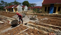 Tampak seorang pekerja yang mengenakan kostum Spiderman membawa troli berisi adonan semen.