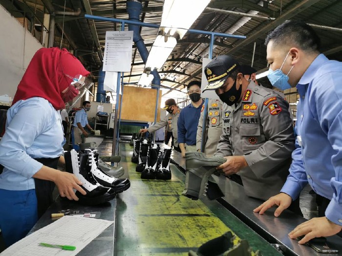 Anggota polisi melihat produksi sepatu dalam negerib