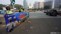 Polisi tampak membentangkan spanduk sosialisasi kebijakan ganjil genap.