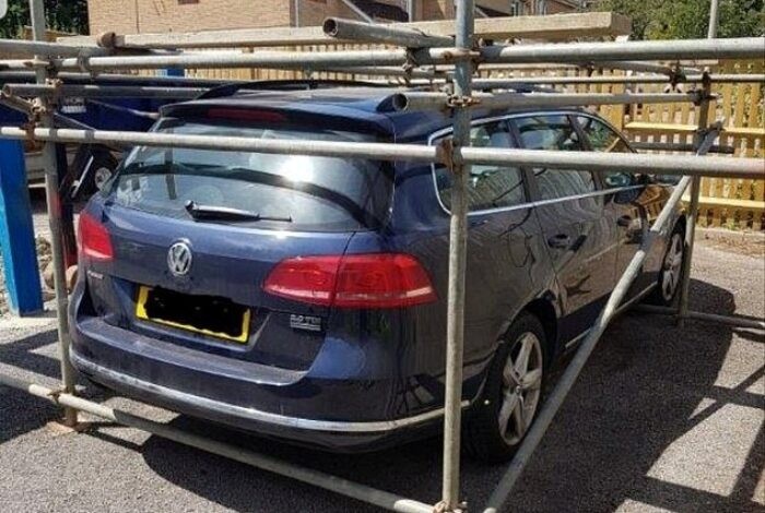 Sebuah Volkswagen Passat dikerangkeng pipa besi karena dianggap parkir sembarangan
