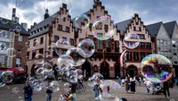 Seorang seniman jalanan membuat gelembung di depan balai kota di Frankfurt, Jerman. AP Photo/Michael Probst  