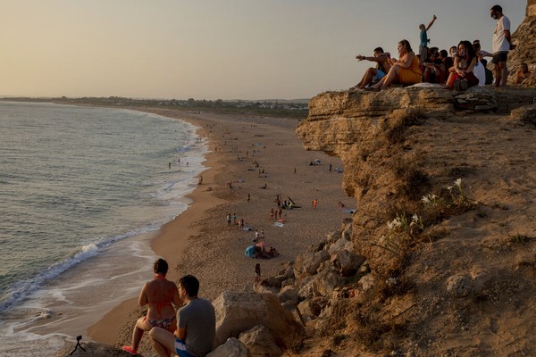 Orang-orang menyaksikan matahari terbenam dengan duduk di tebing di samping Mercusuar Trafalgar di Los Caños de Meca, kota Barbate di provinsi Cadiz, Spanyol. AP Photo/Emilio Morenatti Orang-orang menyaksikan matahari terbenam dengan duduk di tebing di samping Mercusuar Trafalgar di Los Caños de Meca, kota Barbate di provinsi Cadiz, Spanyol. AP Photo/Emilio Morenatti