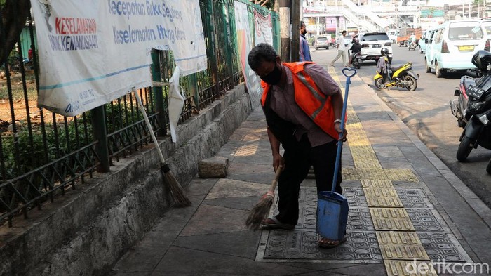 Tidak Pakai Masker, Pria Ini Dihukum Menyapu Jalan Satpol PP melakukan razia masker di Kampung Melayu, Jakarta, Jumat (7/8). Warga yang kedapatan tidak memakai masker dihukum dengan membersihkan trotoar.