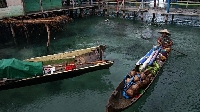 Nadi Riakurabi (kanan) menjajakan dagangannya dari atas perahu di perkampungan di atas laut suku Bajo, Torosiaje, Kabupaten Pohuwato, Gorontalo, Minggu (9/8/2020). Pedagang perahu keliling yang menjual bumbu dapur, sayuran dan bahan pangan lainnya tersebut menjadi salah satu alternatif warga untuk memenuhi kebutuhan harian selain ke pasar yang berada di daratan. ANTARA FOTO/Adiwinata Solihin/foc.