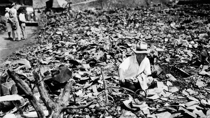 FILE - In this Sept. 17, 1945, file photo, a Japanese civilian salvages a piece of what was once a childs tricycle in Nagasaki, Japan.  The city marks the 75th anniversary of the U.S. atomic bombing of Aug. 9, 1945. It was a second nuclear bomb dropped by the U.S. three days after it made the world’s first atomic attack on Hiroshima. Japan surrendered on Aug. 15, ending World War II and its nearly a half-century aggression toward Asian neighbors.  Dwindling survivors, whose average age exceeds 83, increasingly worry about passing their lessons on to younger generations. (AP Photo/Stanley Troutman, Pool, File)