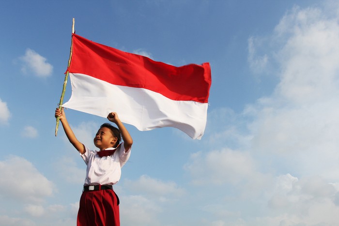 Beautiful young mother with her daughter celebrating indonesia independence day by raising flag under the sunset sky