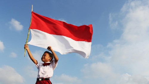 Beautiful young mother with her daughter celebrating indonesia independence day by raising flag under the sunset sky