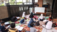 Seorang guru memberikan penjelasan soal materi pelajaran kepada para siswa.