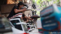 Andi tampak melakukan pengecetan pada produk miniatur bus miliknya.